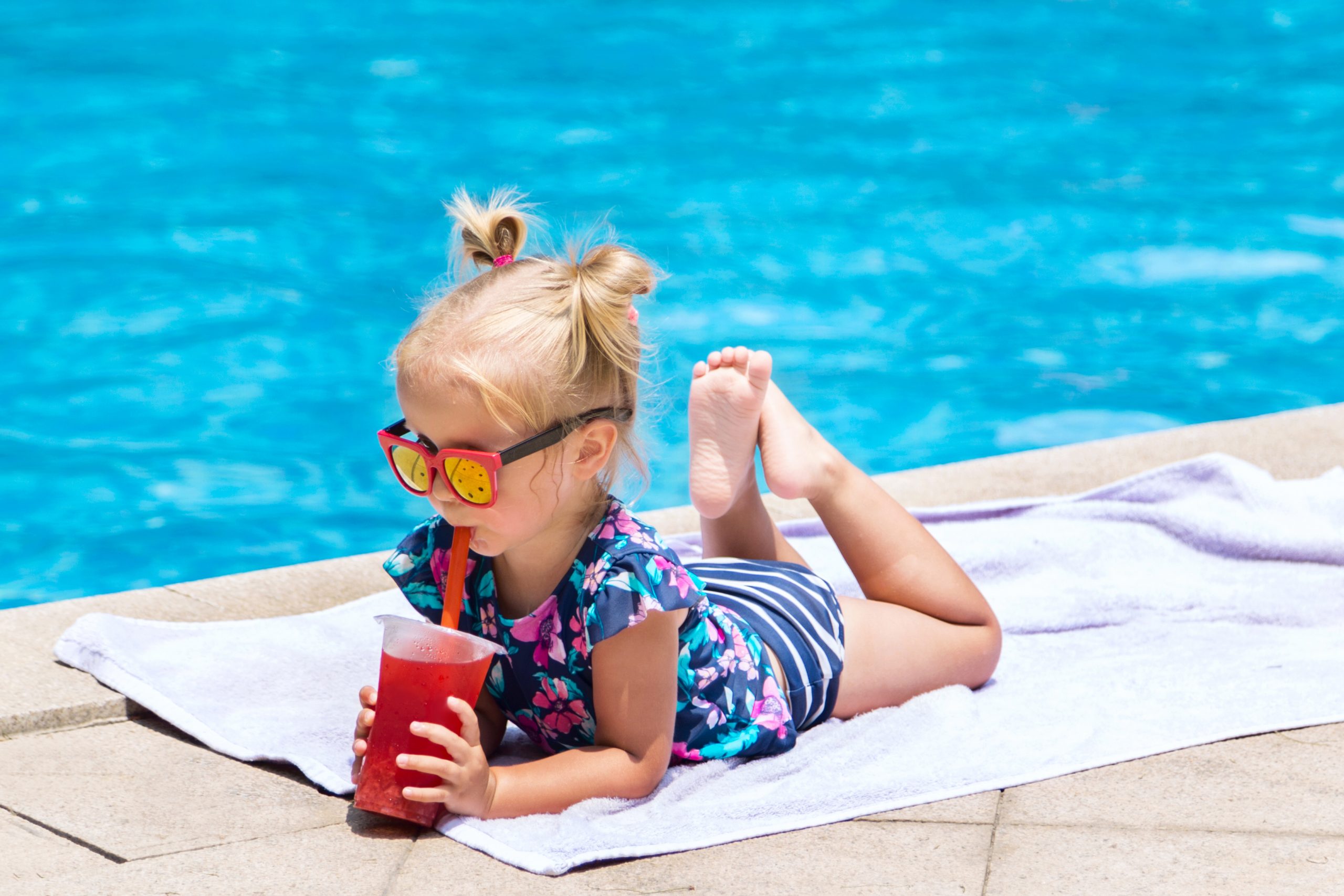 Little girl with cocktail at the swimming pool