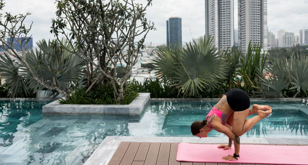 woman doing ypga pose near the pool